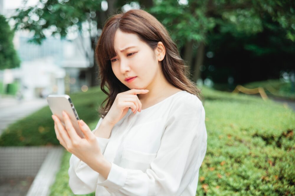 スマホを見て困っている女性